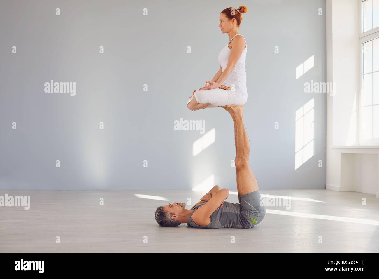 Yoga-Paare üben in einer Studioklasse auf dem Boden Acro Yoga. Stockfoto