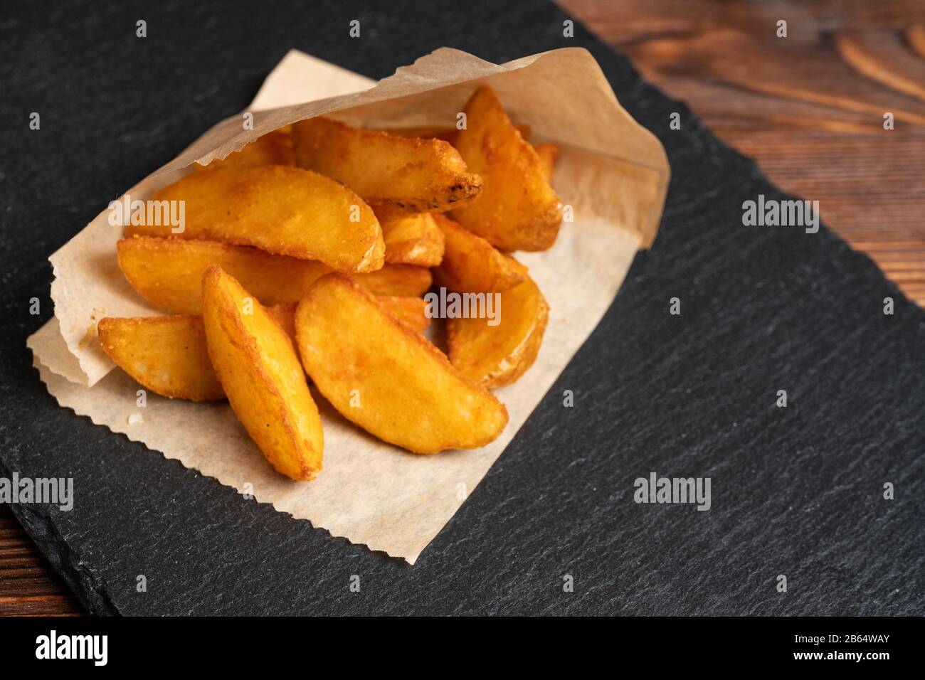 Kartoffel rustikales Tafelgeschirr Schiefer, schwarzer Stein auf Holzgrund. Nahaufnahme. Stockfoto