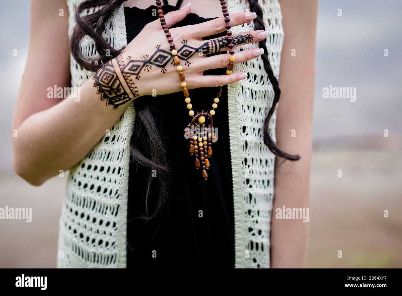 Nahaufnahme von weiblichen Händen mit Henna tattoo mehndi auf hellblauem Kleid, sitzende Frau im Boho-Stil, Beauty-Style-Fotografie Stockfoto