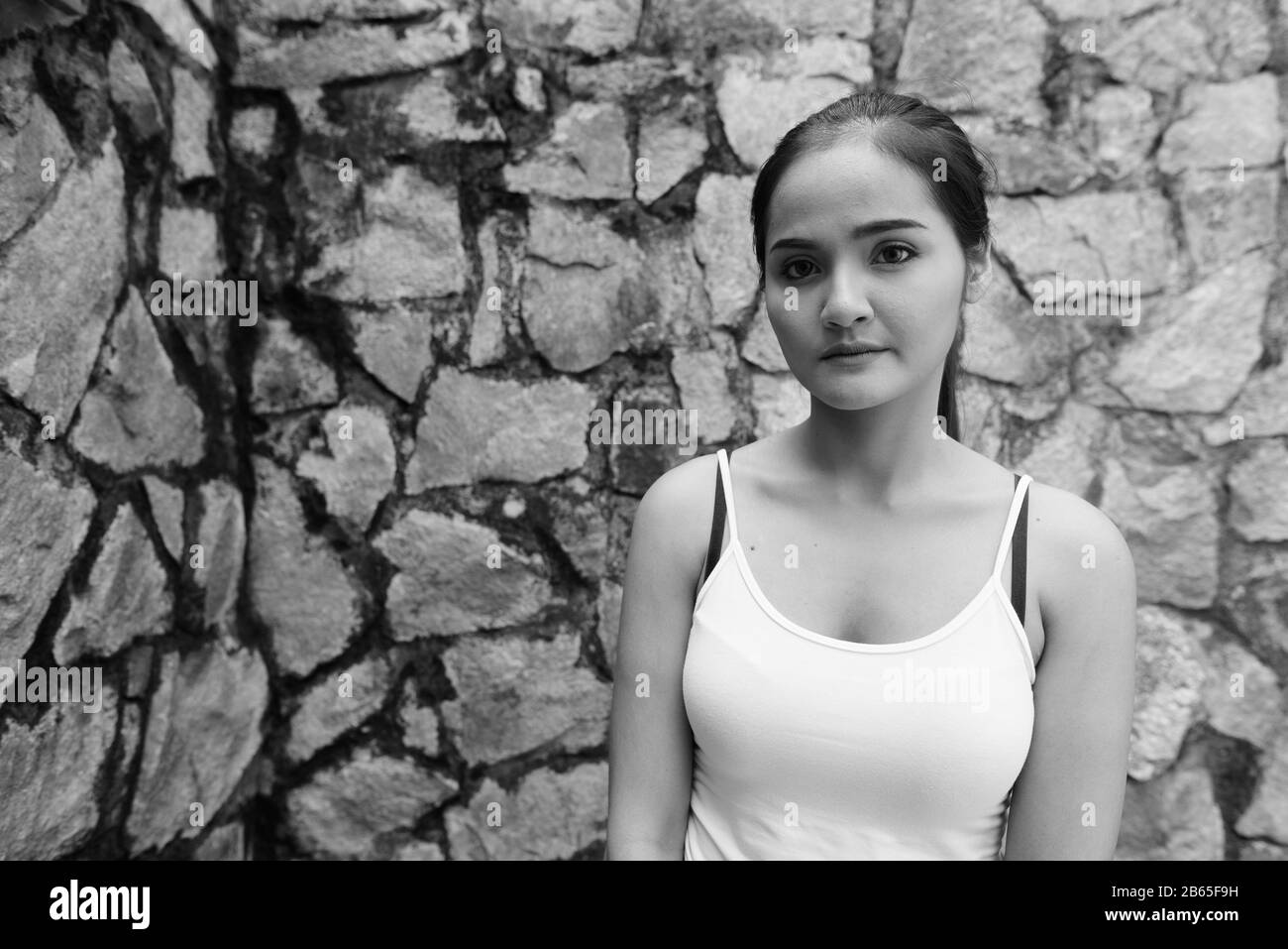 Junge schöne Asiatin gegen Steinmauer Stockfoto