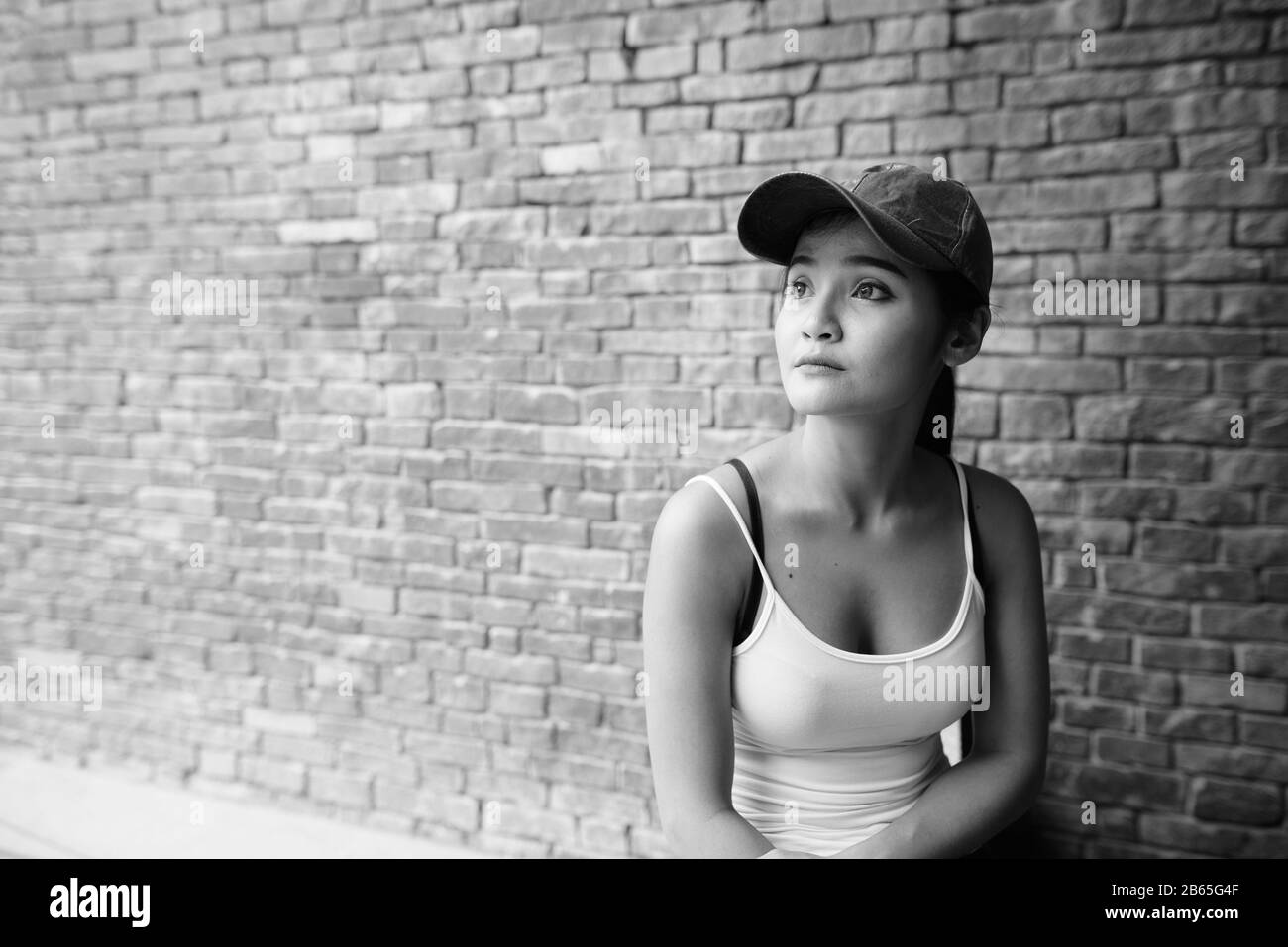 Junge schöne asiatische Touristenfrau gegen Ziegelmauer Stockfoto