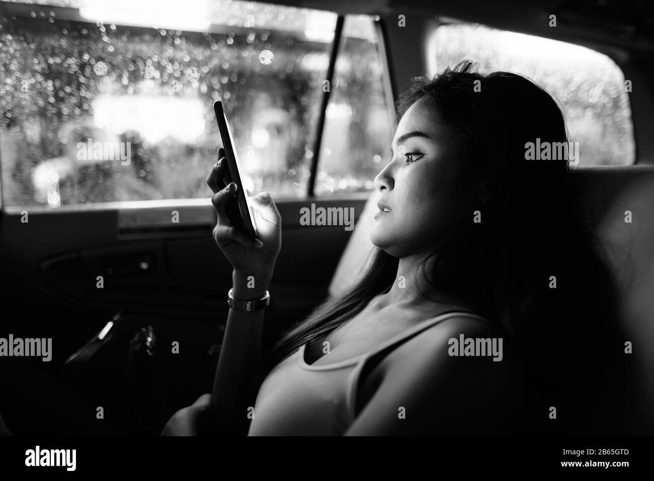 Junge, schöne asiatische Touristenfrau, die im Auto telefoniert Stockfoto