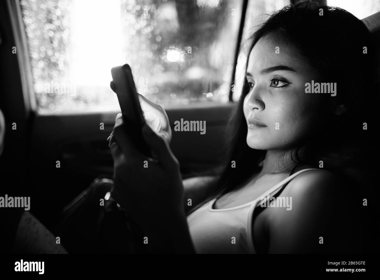 Junge, schöne asiatische Touristenfrau, die im Auto telefoniert Stockfoto