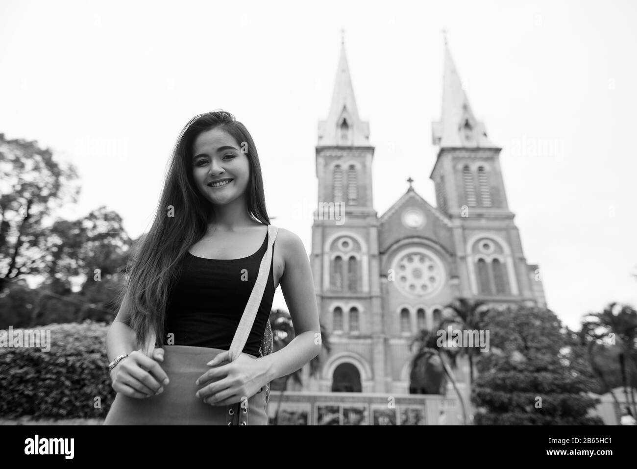 Fröhliche junge, schöne asiatische Touristin gegen den Blick auf die Kathedrale Stockfoto