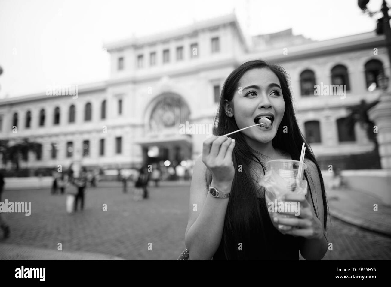 Fröhliche junge, schöne asiatische Touristin, die Straßennahrung isst Stockfoto