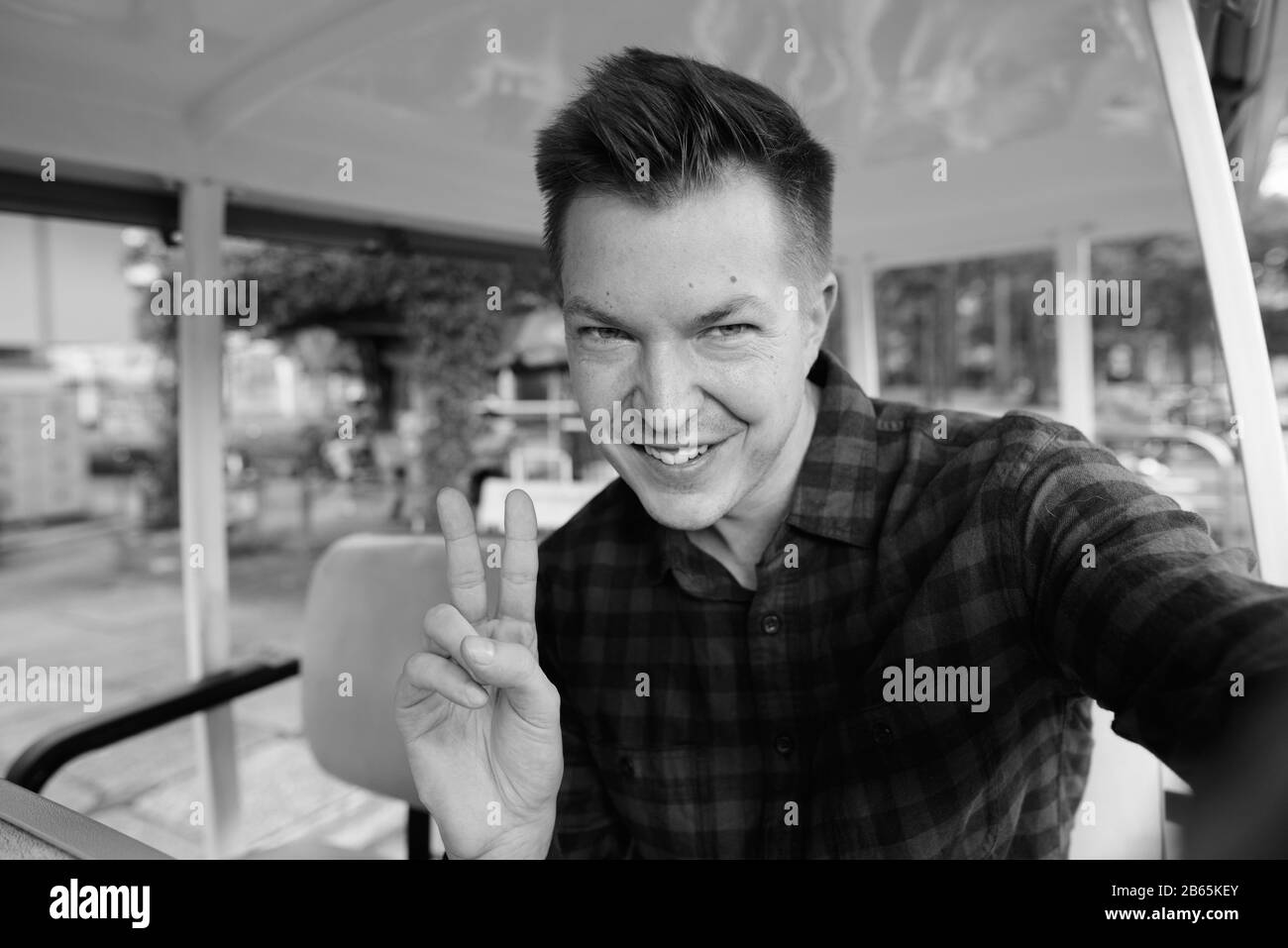 Fröhlicher junger, gutaussehender Tourist, der ein lustiges Gesicht in den Wagen stellt Stockfoto