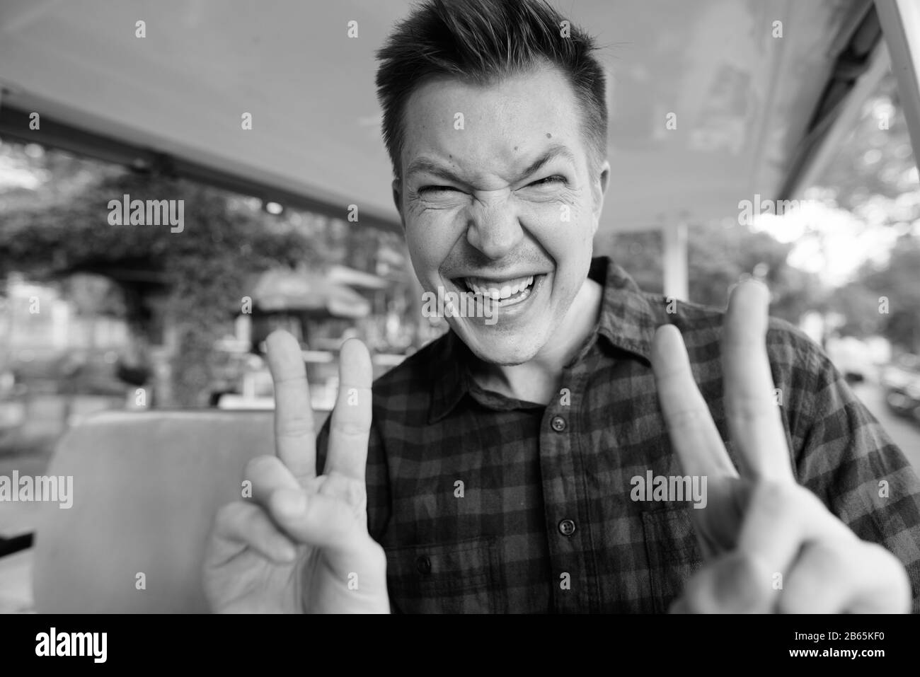 Fröhlicher junger, gutaussehender Tourist, der ein lustiges Gesicht in den Wagen stellt Stockfoto