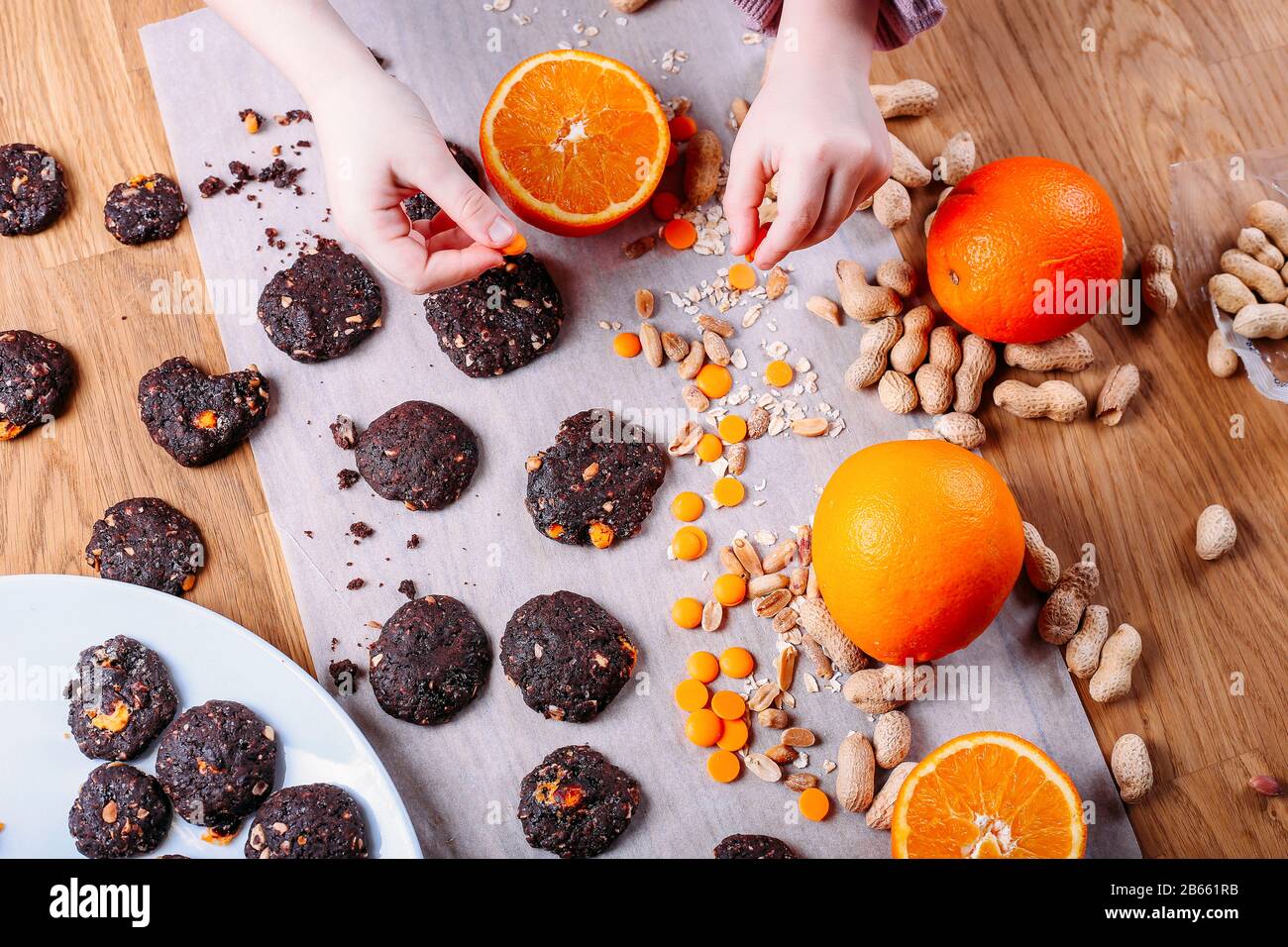Handgefertigte Schokoladenplätzchen mit Orange und Zimt und Nüssen. Süßigkeiten, Schokolade, Zitrusfrüchte, Zimt. Kinder nehmen selbst gebackenen Buskuit mit Stockfoto