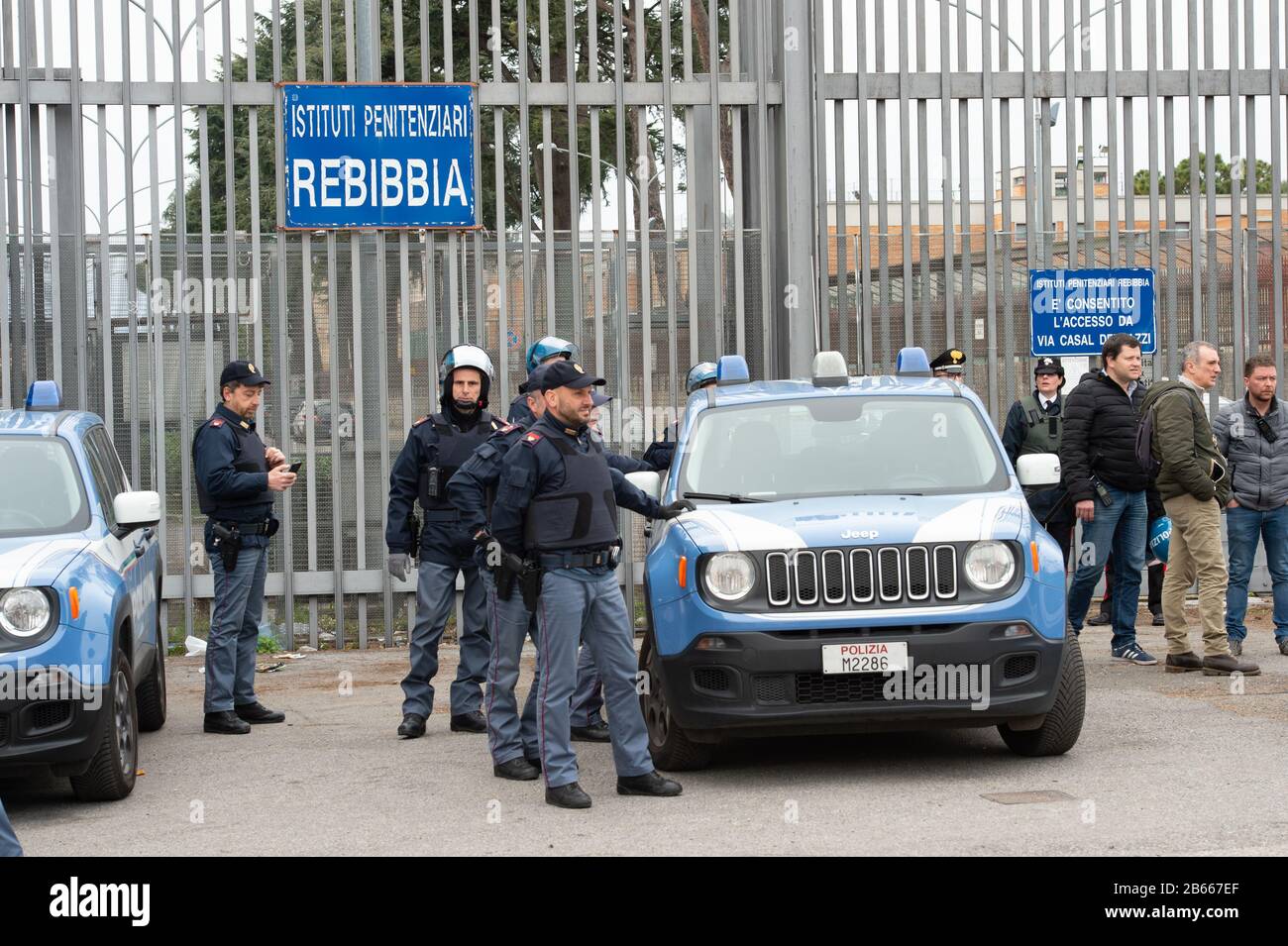 Polizei bei Familienangehörigen von Häftlingen rallyin vor dem Eingang zum römischen Gefängnis in Rebibbia, wo ein Häftlingsaufruhr stattfand. In vielen italienischen Gefängnissen kam es zu Krawallen. Die Inhaftierten protestieren gegen die Blockierung von Gesprächen mit Familienmitgliedern, für die von Alternativen und Gefängnismaßnahmen sowie für die nicht vorhandenen epidemischen Präventionsmaßnahmen innerhalb der Gefängniseinrichtungen. Wo Depotmittel ohne Handschuhe und Schutzmasken sind und Überdrängungskräfte das Zusammenleben in engen Räumen erzwangen. Stockfoto