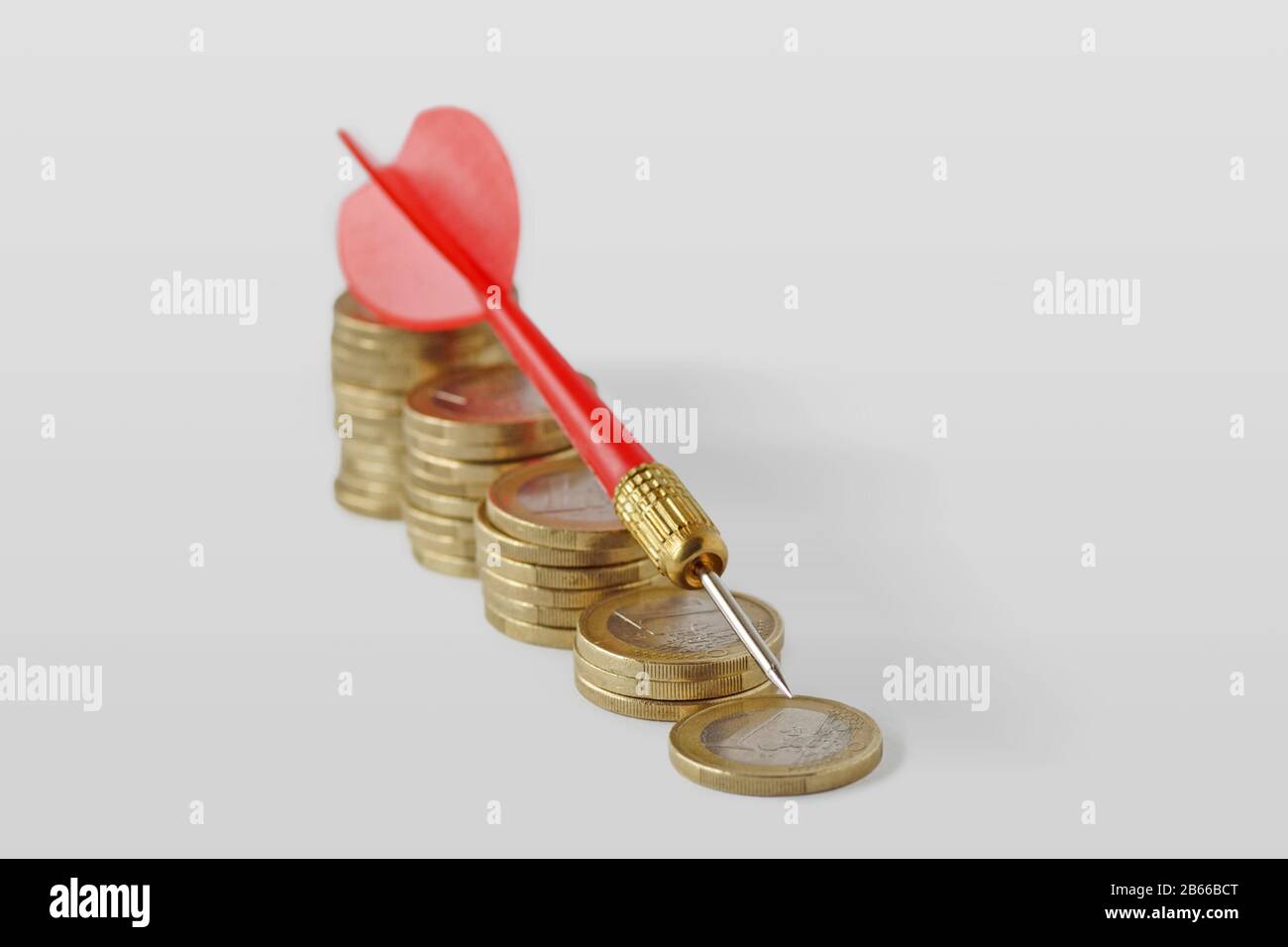 Nahaufnahme des roten Darts bei sinkenden gestapelten Münzen - Geldverlust Konzept Stockfoto