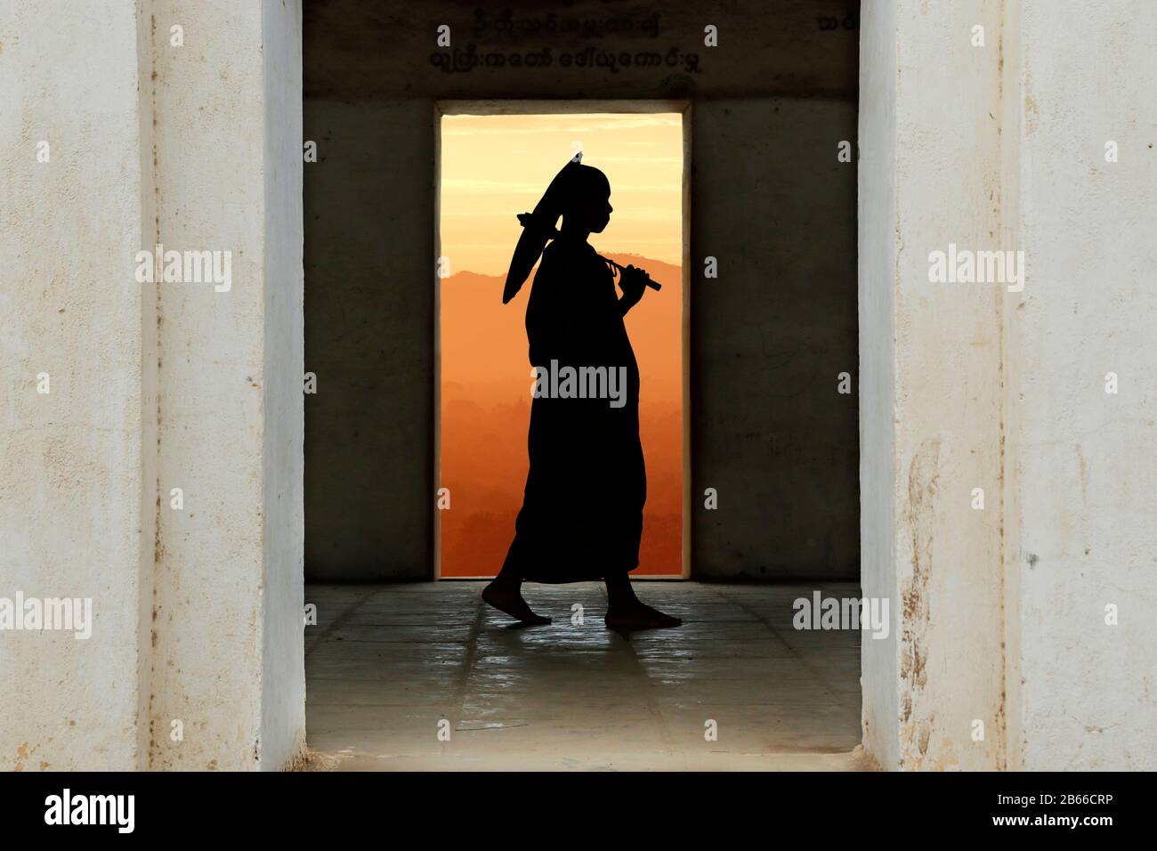 Silhouette des Monchs mit Regenschirm, der im Tempel spazieren geht Stockfoto