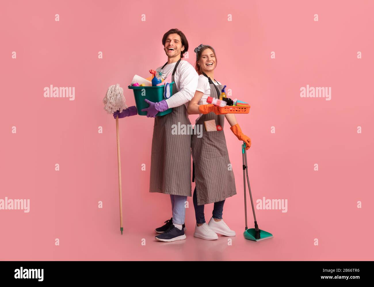 Glückliches junges Paar mit vielen Waschmitteln, die über rosafarbenem Hintergrund posieren Stockfoto