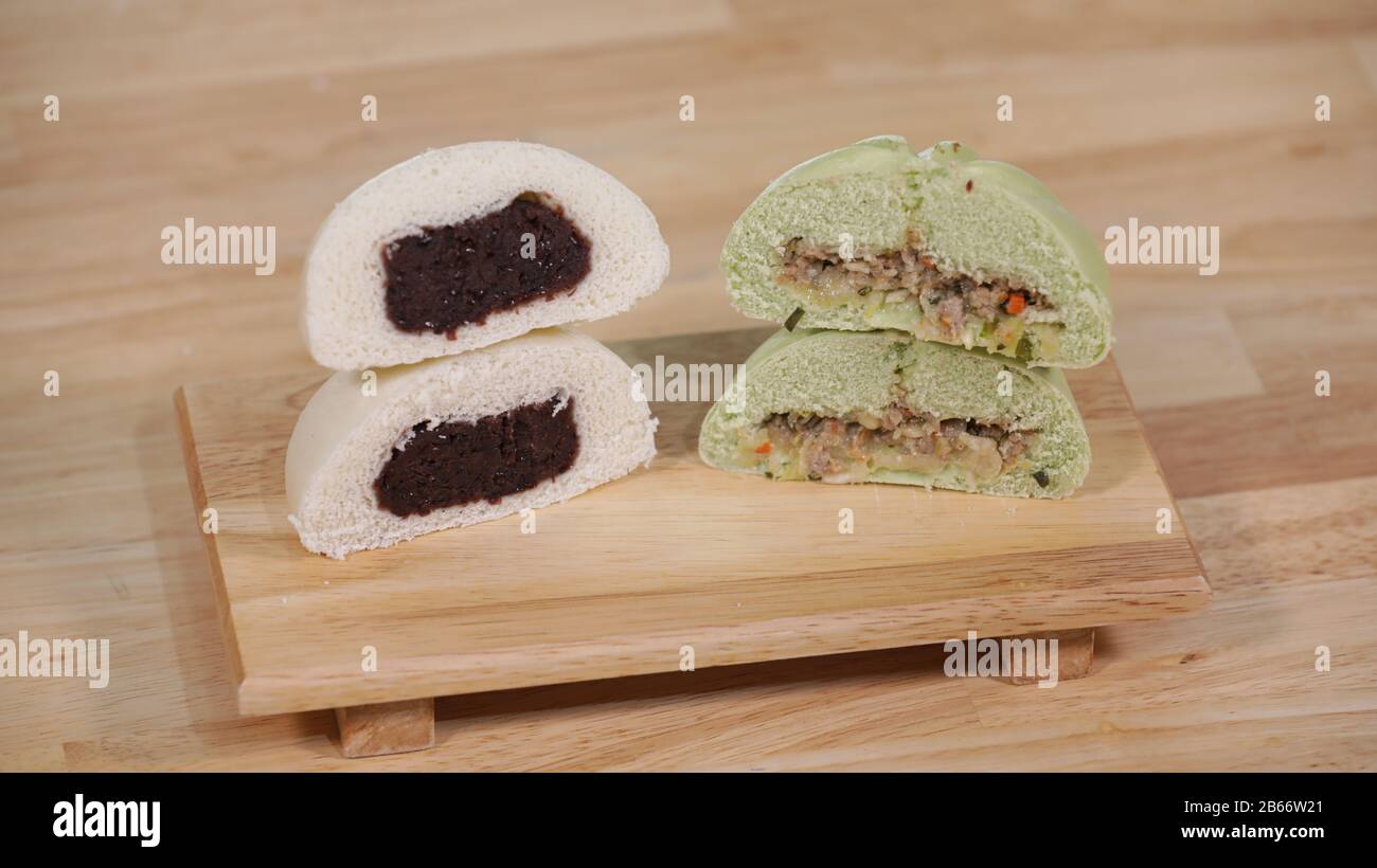 In Scheiben geschnittene koreanische Traditionelle Gedämpfte Brötchen mit roten Bohnen- und Gemüsefüllungen auf einem Holzteller Stockfoto