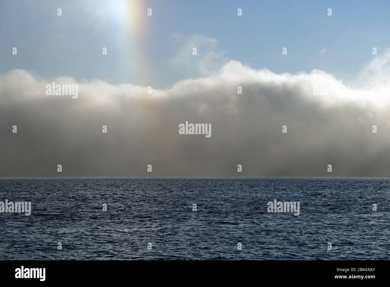 Blick auf den kleinen Regenbogen, der Sonnenhundeeffekt über den Morgennebel genannt wird, der über den Fjord steigt. Stockfoto