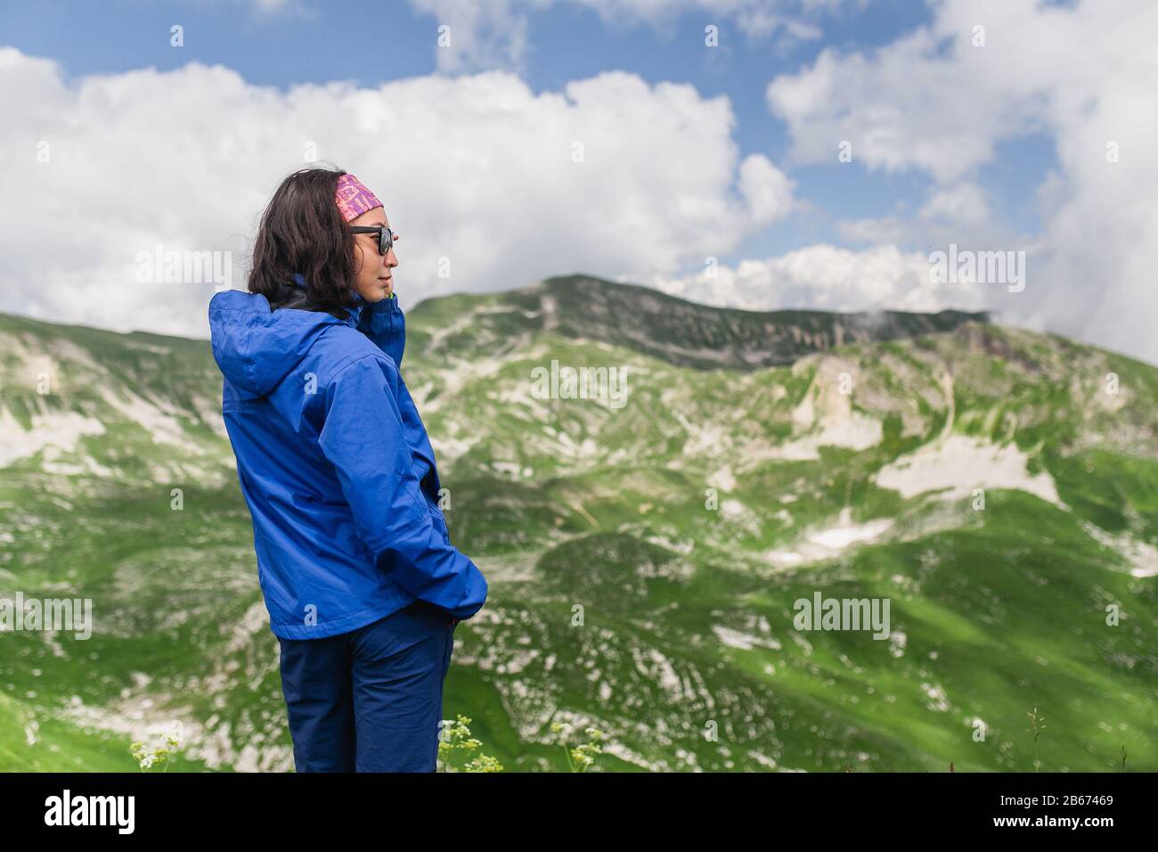 Frau, die durch die hochalpinen Wiesen am Gipfel des Berges wandert Stockfoto