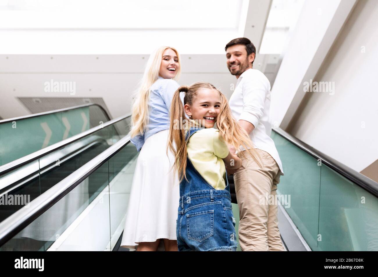 Eltern Und Tochter Lächeln Auf Beweglichen Treppen In Mall Stockfoto