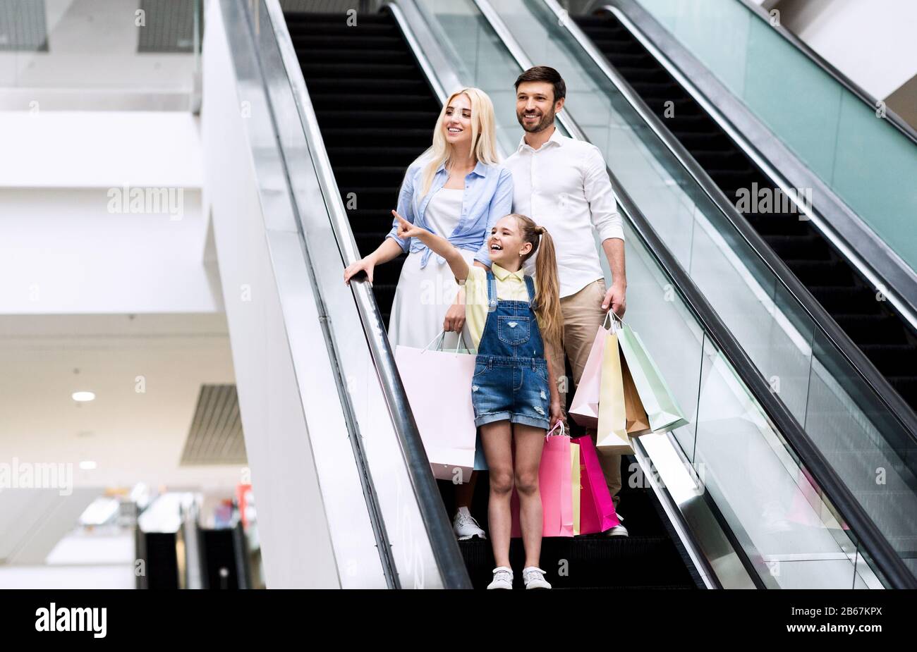 Tochter, Die Eltern Etwas Zeigt, Das Auf Einer Sich Bewegenden Treppe In Mall Steht Stockfoto