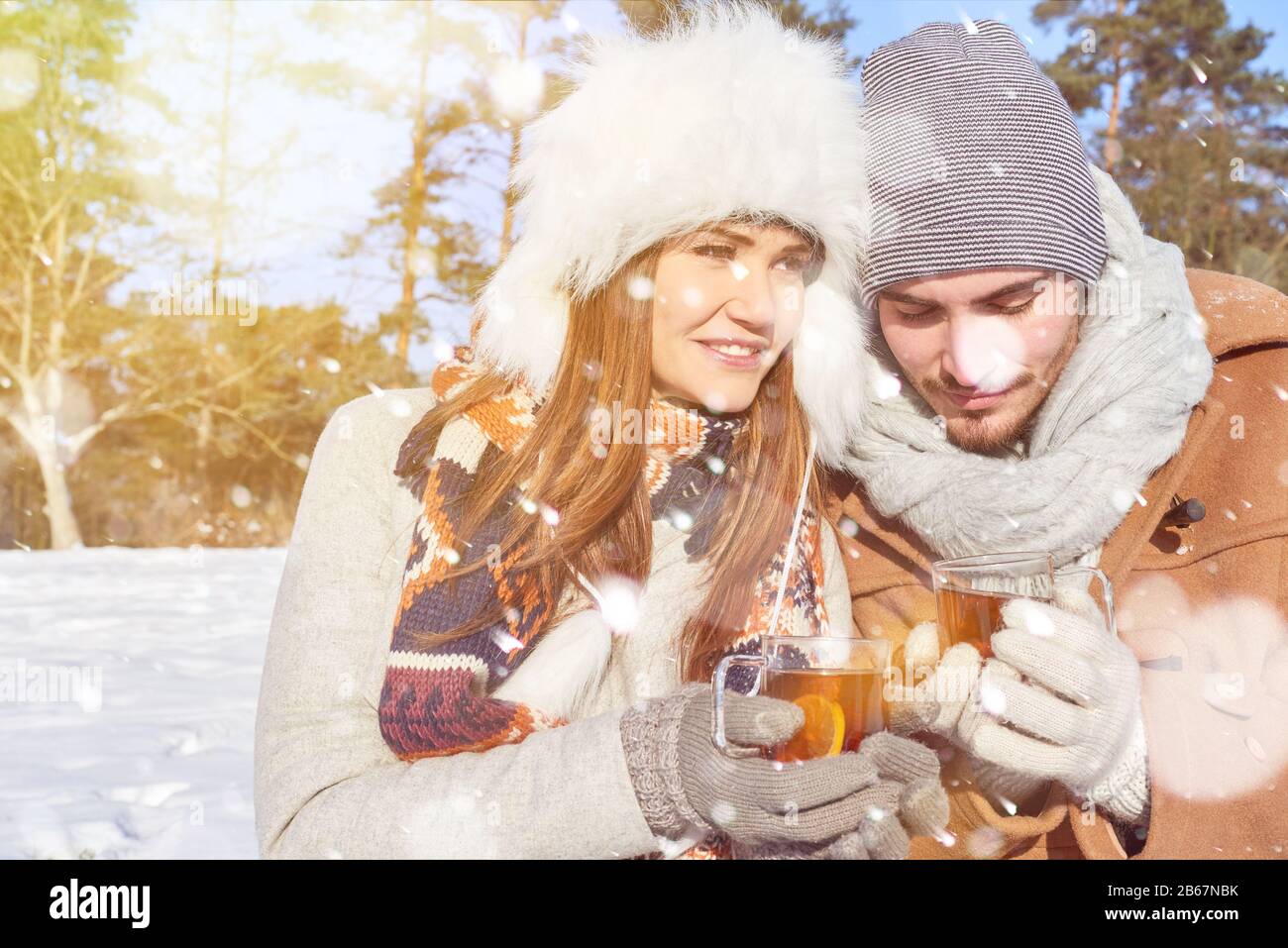 Mann und Frau trinken im Winter zusammen heißen Tee im Schnee Stockfoto