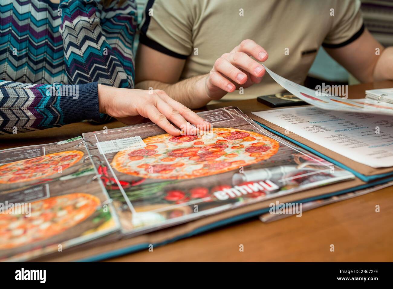 23. Februar 2017, UFA, RUSSLAND: Zwei Personen wählen im Restaurant "Eigenfirma" eine Pizza aus der Speisekarte Stockfoto