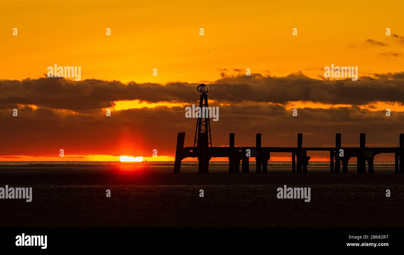 Ein goldener Himmel, während die Sonne hinter der Silhouette des viktorianischen Piers in St Annes on Sea in Lancashire england untergeht Stockfoto