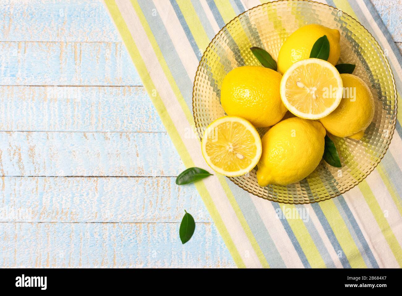 Schüssel mit frischen ganzen und halben Zitronen auf hellblauem Holzhintergrund. Draufsicht mit Kopierbereich. Stockfoto