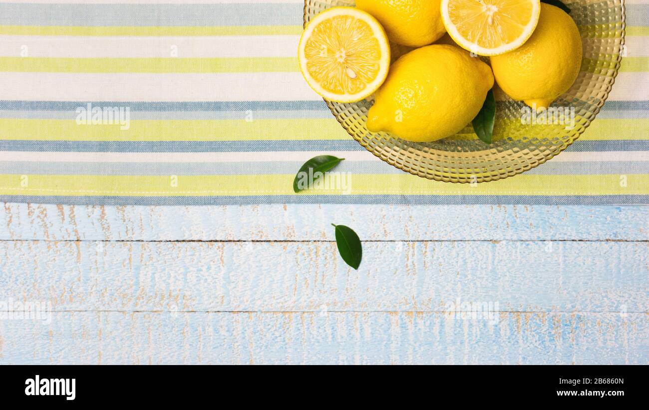 Schüssel mit frischen ganzen und halben Zitronen auf hellblauem Holzhintergrund. Draufsicht mit Kopierbereich. Stockfoto