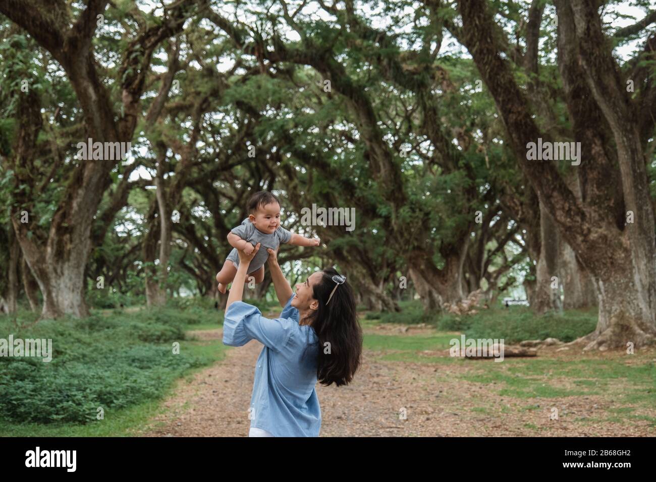 Mutter lacht, während sie ein Baby festhält, während sie gemeinsam Urlaub macht Stockfoto