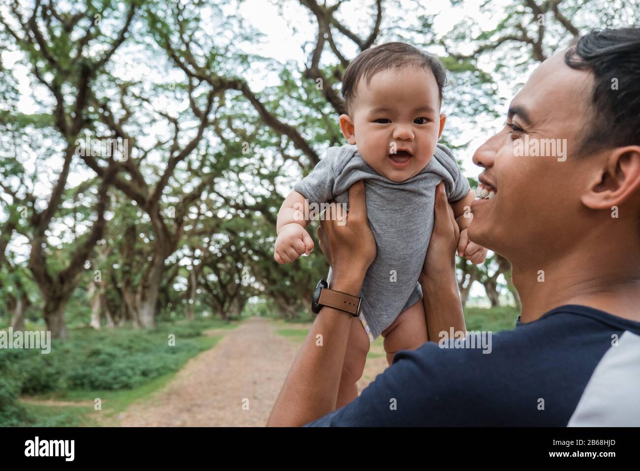 Vater lacht, während er ein Baby festhält, während er gemeinsam Urlaub macht Stockfoto