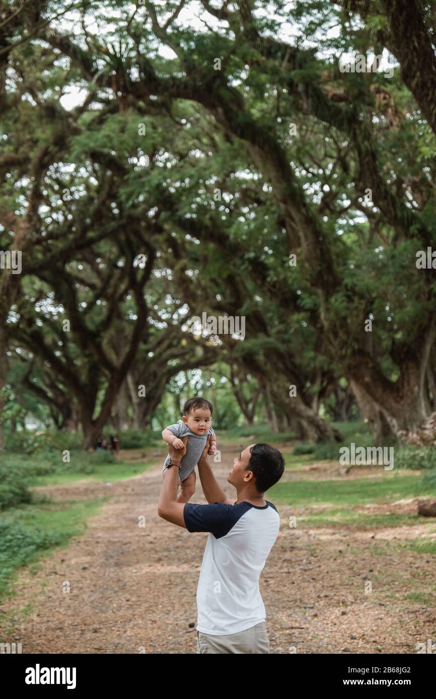 Der asiatische Vater holt das Baby seiner Tochter ab, wenn er im Park spazieren geht Stockfoto