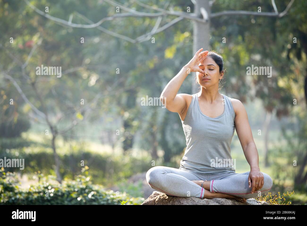 Frau, die Yoga in lotus-position im Park praktiziert Stockfoto