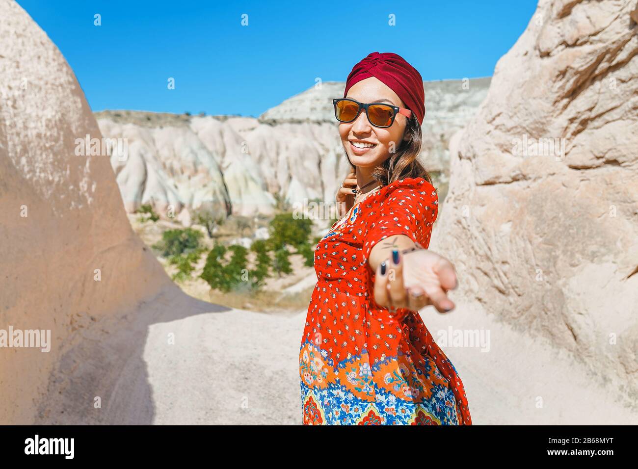 Asiatische weibliche Reisende in der Wüste des Nahen Ostens im Nationalkleid mit Turban folgen mir Stockfoto