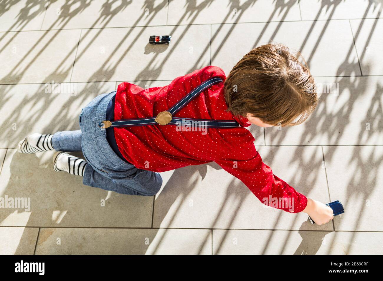 6 Jahre alter Junge, der mit Spielzeugautos auf der Terrasse spielt Stockfoto