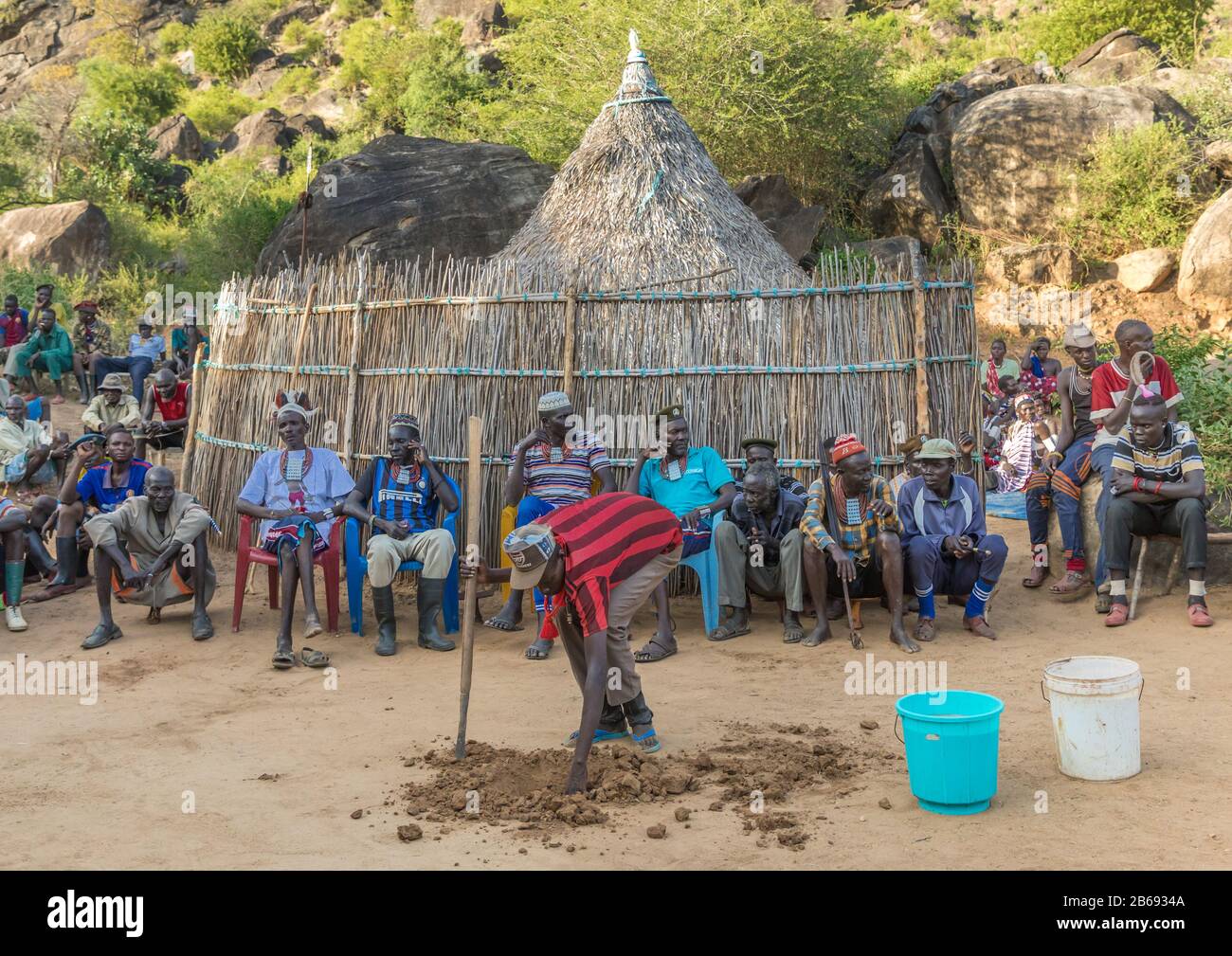 Larim Stammmann, der ein Loch zum Empfang eines Krugs während einer Hochzeitsfeier macht, Boya Mountains, Imatong, Südsudan Stockfoto