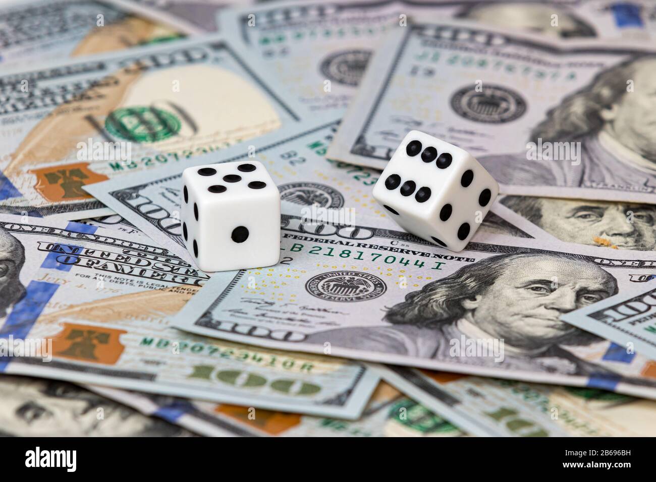 Zwei weiße Würfel auf 100-Dollar-Rechnungen. Konzept von Glücksspiel, Finanzen, Aktienmarkt-Investitionsrisiko und Rendite Stockfoto