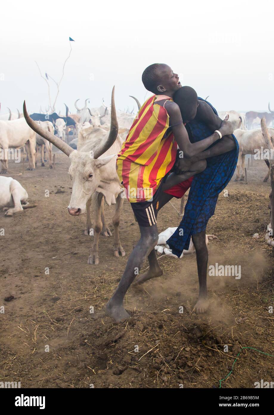 Mundari Stammjungen, die in einem Viehlager, Central Equatoria, Terekeka, Südsudan, wringen Stockfoto