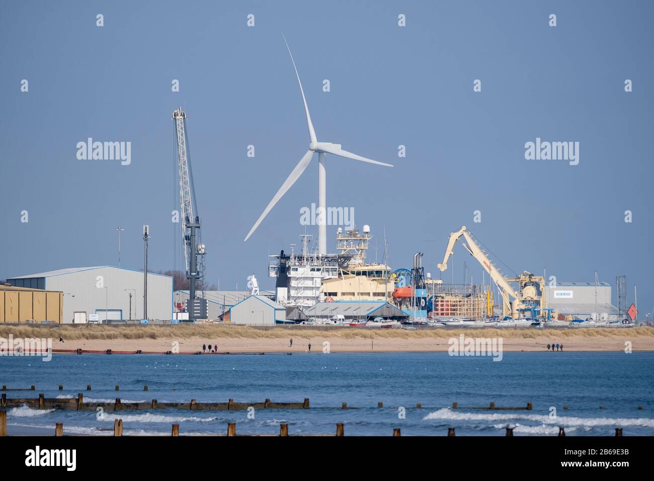 Windturbine hoch über Schiffen und Lagerhäusern am Hafen von Blyth an der Küste von Northumberland Stockfoto