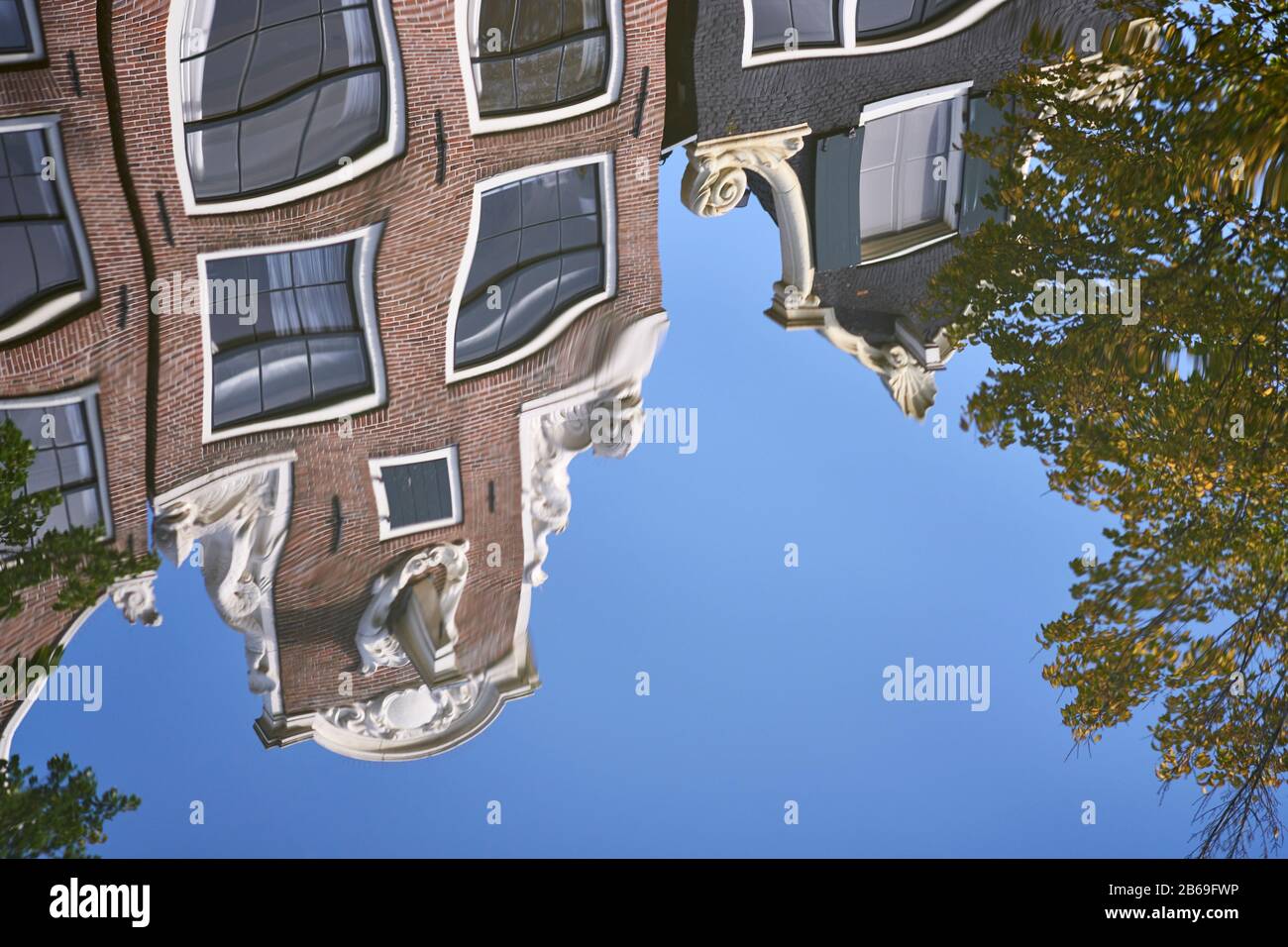 Wellenförmige Reflexionen von Giebeln an typischen Häusern in Amsterdam, mit Delfinen. Am Brouwersgracht Kanal Stockfoto