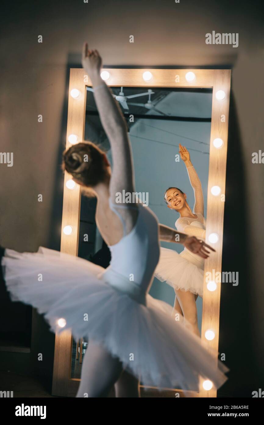 Junge Ballerina in weißem Kleid mit perfektem Körper tanzt im Studio Stockfoto