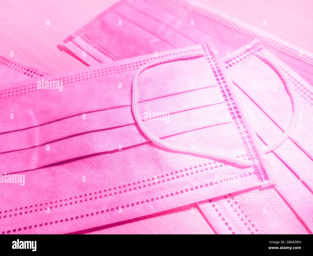 Medizinische Gesichtsmasken in Rosa auf dem Tisch. Seitenansicht, Nahaufnahme. Stockfoto