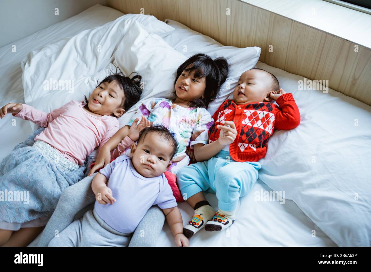 Vier asiatische Kinder spielen gern und scherzten im Bett, wenn sie aufwachen Stockfoto