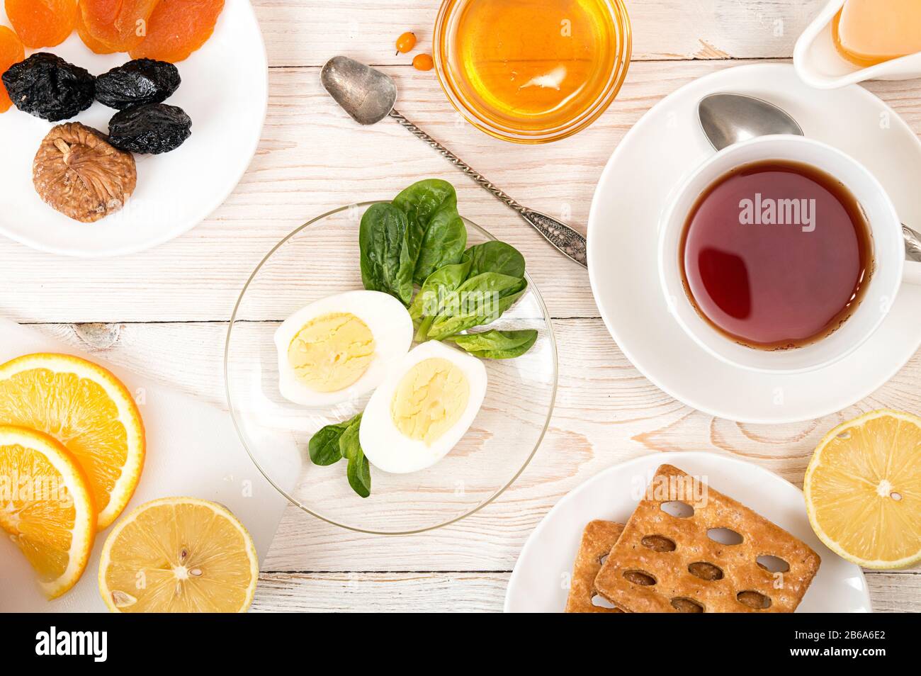 Gesundes Frühstück. Gekochte Eier mit Spinat, Orangensaft, Tee, Honig, Kekse und getrocknete Früchte auf weißer Tisch. Gesunde Organische natürliche Nahrung Co Stockfoto