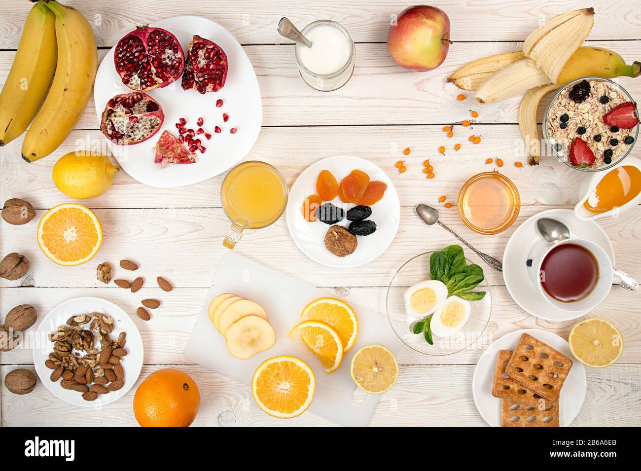 Gesundes Frühstück. Gekochte Eier, Müsli, Orangensaft, Tee, Joghurt, Honig, Nüsse und frische Früchte auf weißer Tisch. Gesunde Organische natürliche Nahrung Co Stockfoto