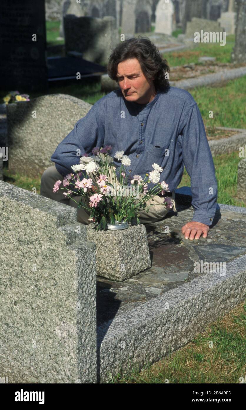 Mann an Grabseite auf dem Friedhof Stockfoto