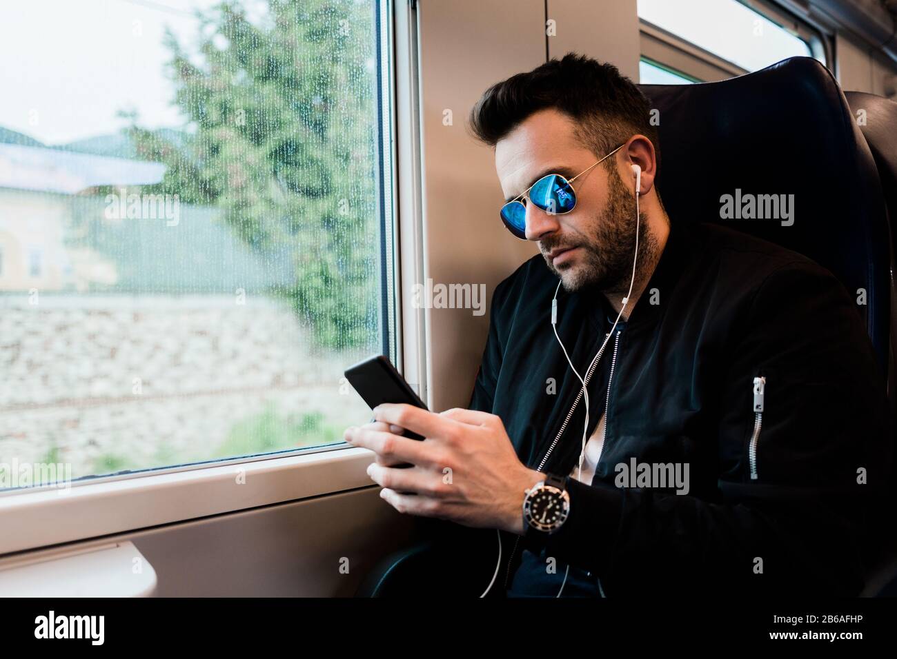 Junger Mann, der mit dem Zug unterwegs ist und Ohrhörer trägt Stockfoto