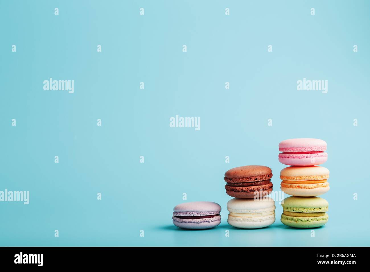 Mehrfarbige französische Makaroni Makaroni Kekse sind in einer Pyramide auf blauem Grund angeordnet. Freier Speicherplatz, Nahaufnahme. Minimalistisches Konzept Stockfoto