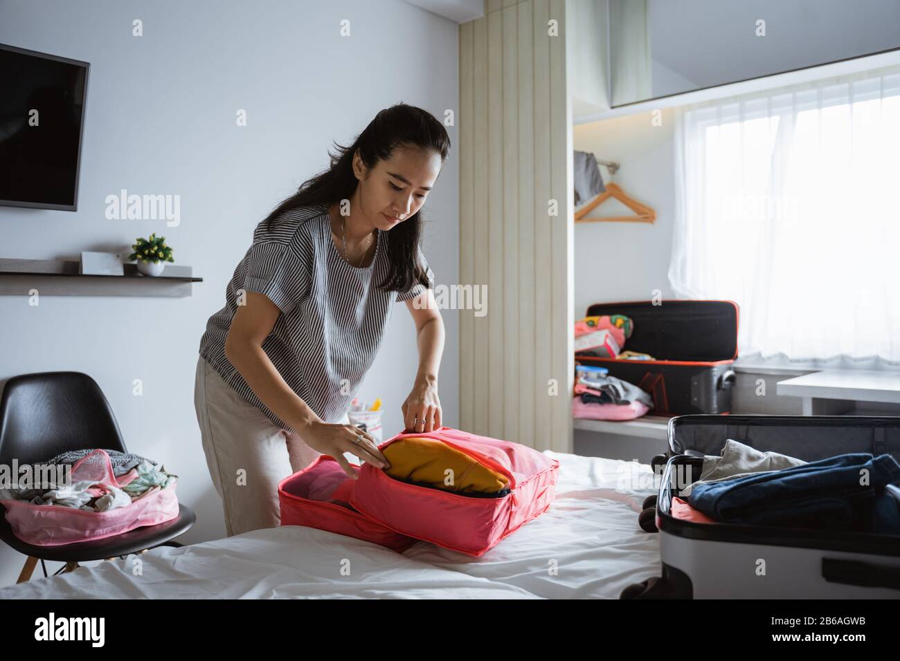 Asiatische Mutter bereitet Kleidung und Taschen für Urlaubsreisen vor Stockfoto
