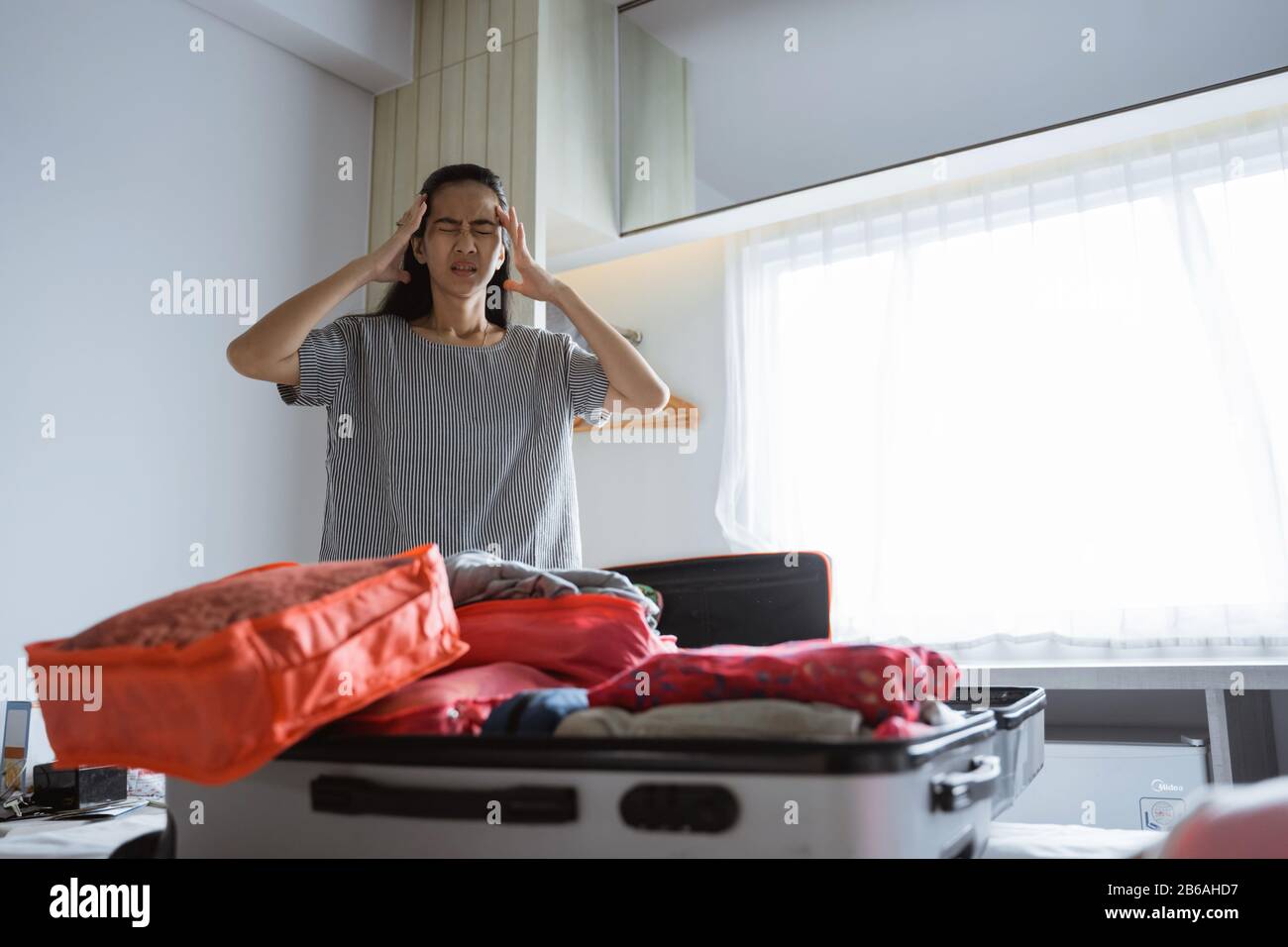 Asiatische Mutter hat Kopfschmerzen, wenn sie Kleidung und Taschen für Reisen vorbereitet Stockfoto Asiatische Mutter hat Kopfschmerzen, wenn sie Kleidung und Taschen für Reisen vorbereitet Stockfoto
