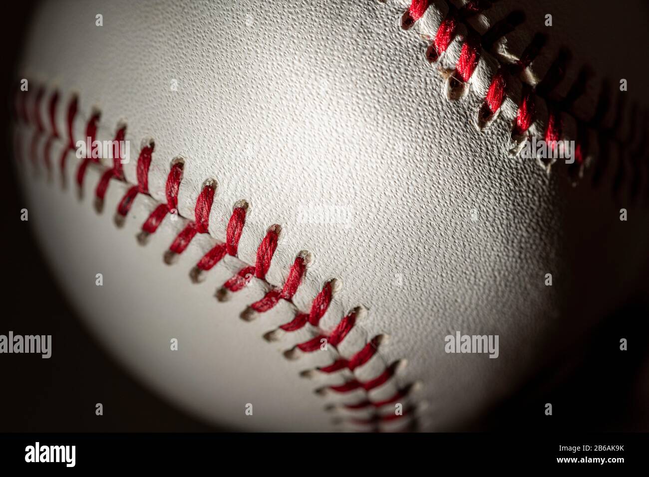 Ein weißer Baseball-Leder auf schwarzem Hintergrund Stockfoto