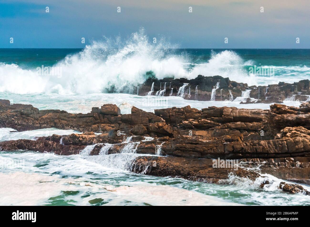 Die Wellen krachen wild am felsigen Ufer an Storms River Mouth, Tsitsikampa National Park, Südafrika Stockfoto