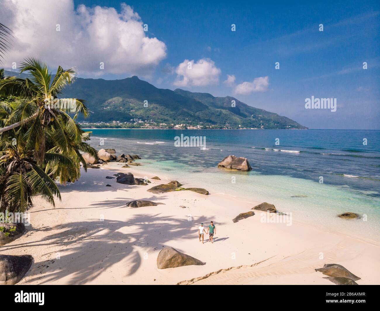 Tropische Inseln auf den Seychellen, Insel Praslins Seychellen, zwei Paare, die mit Palmen am tropischen Strand spazieren gehen Stockfoto